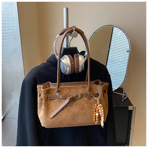 Detailed view of vintage brown suede tote bag with leather strap and colorful bead charm