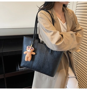 Detail of black large-capacity tote bag with a cute brown plush bear pendant