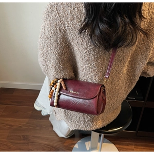 Close-up of wine red retro crossbody bag with colorful wooden beads and brand logo