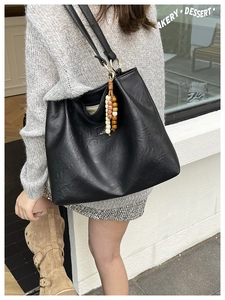 Close-up of black PU leather tote bag featuring a decorative wooden bead tassel and zipper