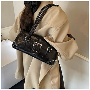 Detail of black patent leather shoulder bag with silver studs on khaki trench coat