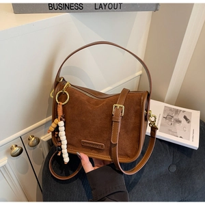 Détail du sac en cuir dépoli marron avec logo KAIAN BAGS et breloque perlée