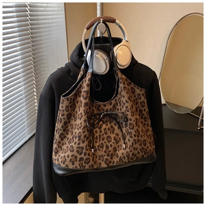 Detailed close-up of a large leopard print tote bag with black leather trim and bow tie