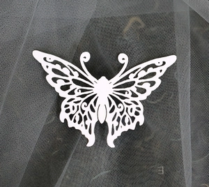 Macro shot of laser-cut white pearl paper butterfly with intricate floral lace pattern