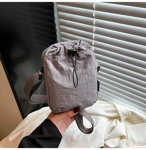Detail of grey nylon crossbody phone bag featuring pleated texture and fashion label
