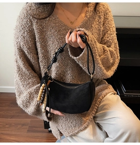 Detail of black suede hobo bag with wooden bead tassel and knotted leather strap