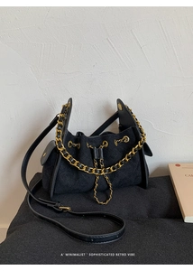 Detailed view of black quilted bucket bag with gold chain and adjustable leather strap