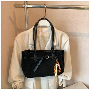 Detail of minimalist black matte suede tote bag with decorative strap and wooden beads