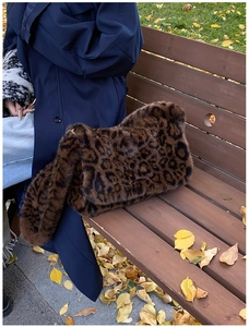 Dettaglio della borsa in ecopelliccia leopardata su panca con foglie d'autunno