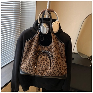 Detail of leopard print tote bag with black bow decoration and leather reinforced handle