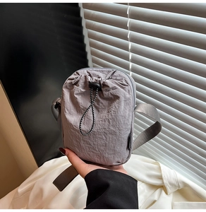 Detailed view of grey textured nylon phone bag featuring adjustable drawstring and wide strap