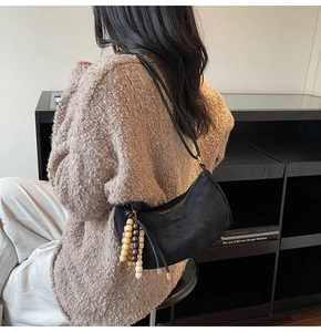Close-up of black matte dumpling bag featuring retro wooden beaded tassel details