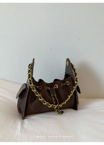 Détail du sac à bandoulière en daim marron foncé avec motif matelassé et chaîne