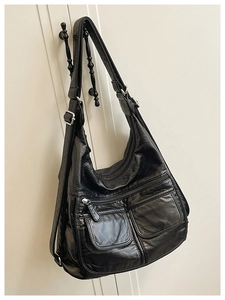 Detail view of large multi-pocket black leather backpack for travel and commuting