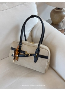 Detail of beige suede Boston bag with black leather straps and retro wooden bead charm