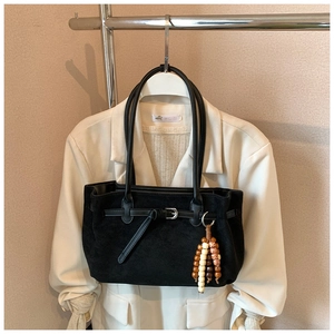 Detail of black matte suede tote bag with silver buckle and beaded tassel charm