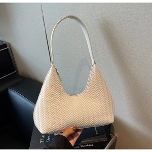 Dettaglio macro della texture intrecciata beige su una borsa sottobraccio chic
