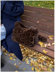 Borsa tote in peluche leopardata su una panchina con foglie autunnali per la moda
