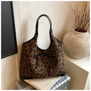 Close-up of leopard print tote bag with black leather bow and handle on a suitcase