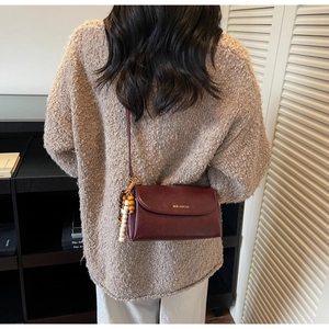 Detail of burgundy leather crossbody bag with wooden beads and gold logo lettering