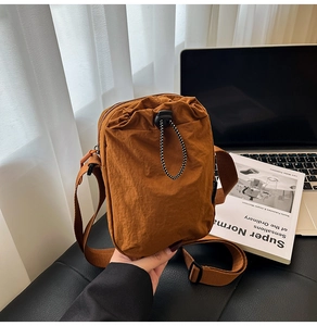 Close-up of caramel nylon crossbody bag with adjustable drawstring pocket and wide strap