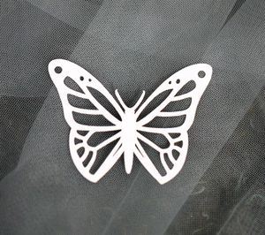 Macro view of white laser-cut butterfly decorative card on dark grey mesh fabric
