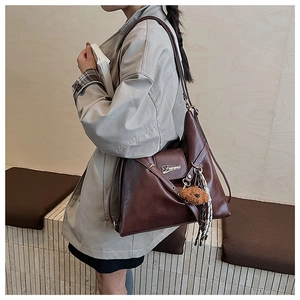 Détail du sac fourre-tout vintage marron avec breloque ours en peluche et gland tressé