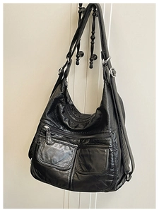 Close-up of black PU leather hobo bag showing functional pockets and vintage texture