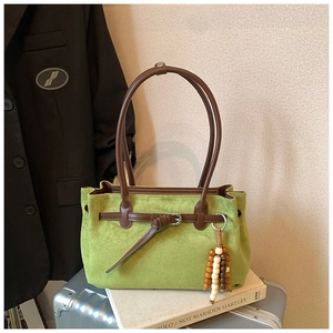 Detail of green suede tote bag with brown leather straps and wooden bead charm accessory
