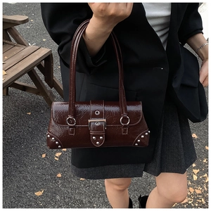 Detail of dark brown patent leather shoulder bag with silver rivets and vintage buckle