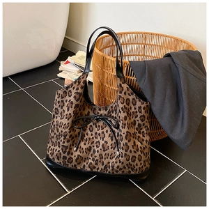 Detail of leopard print tote bag featuring black glossy handles and decorative bow