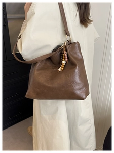 Detail of retro brown underarm bag with glossy texture and decorative wooden beads