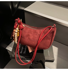 Close-up of burgundy suede hobo bag with bohemian beaded tassel and zipper detail