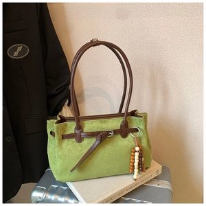 Detail of green suede tote bag with brown leather handles and decorative wooden beads