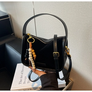 Détail du sac à main vintage noir avec textures en daim et pendentif en perles de bois