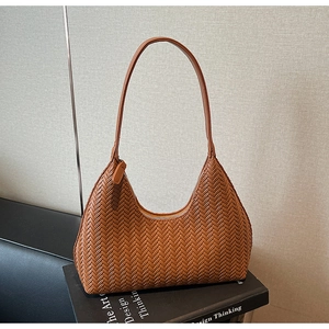 Dettaglio macro della trama intrecciata marrone su una borsa hobo a spalla con cerniera