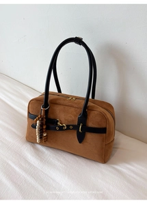 Detail of suede Boston bag featuring vintage gold buckles and a beaded tassel charm