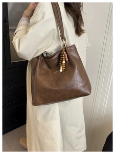 Detail of vintage brown leather tote bag with colorful wooden beads and brand label tag