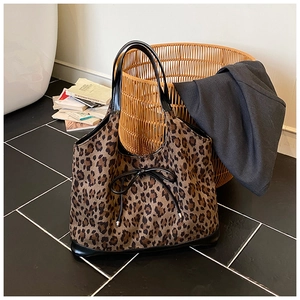 Close-up of leopard print tote bag with black leather straps and a delicate bow detail