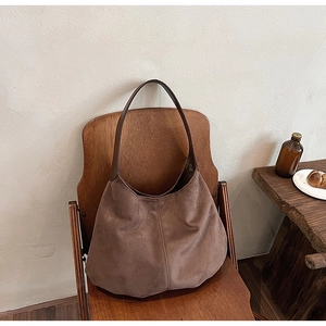 Detailed view of vintage coffee brown suede tote bag on a wooden chair in soft indoor light
