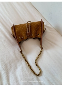 Détail d'un sac seau matelassé marron avec cordon de serrage et bandoulière chaîne