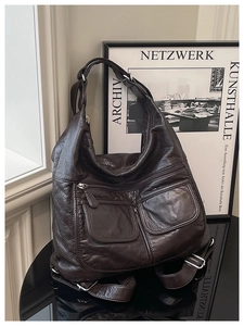 Detail of dark brown lychee leather hobo bag with silver hardware on a reflective surface