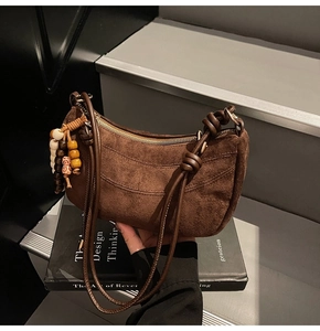Detail of a brown matte suede shoulder bag with colorful wooden beaded tassel charms