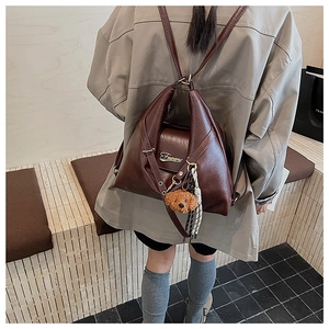 Détail d'un sac à dos en similicuir marron avec pendentif chiot peluche et breloques