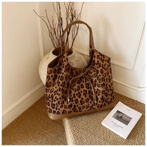 Detail view of large leopard print tote bag with bow drawstring on textured carpet