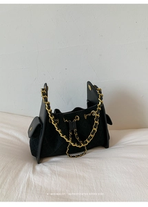 Détail d'un sac à main noir matelassé avec chaîne dorée élégante et poche latérale