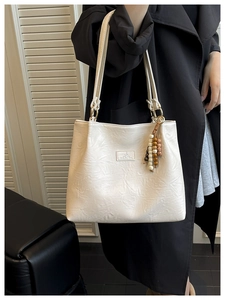 Detail of white PU leather tote with gold rings and retro colorful wooden bead charm