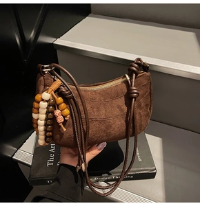 Detail of dark brown suede crescent bag with knotted strap and beaded tassel pendant