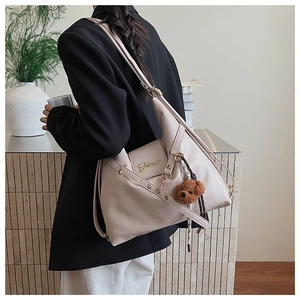 Détail du sac cabas beige en similicuir grainé avec logo doré et charme d'ours brun