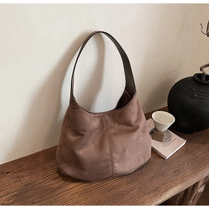 Close-up of brown suede hobo bag texture on wooden table with aesthetic decor